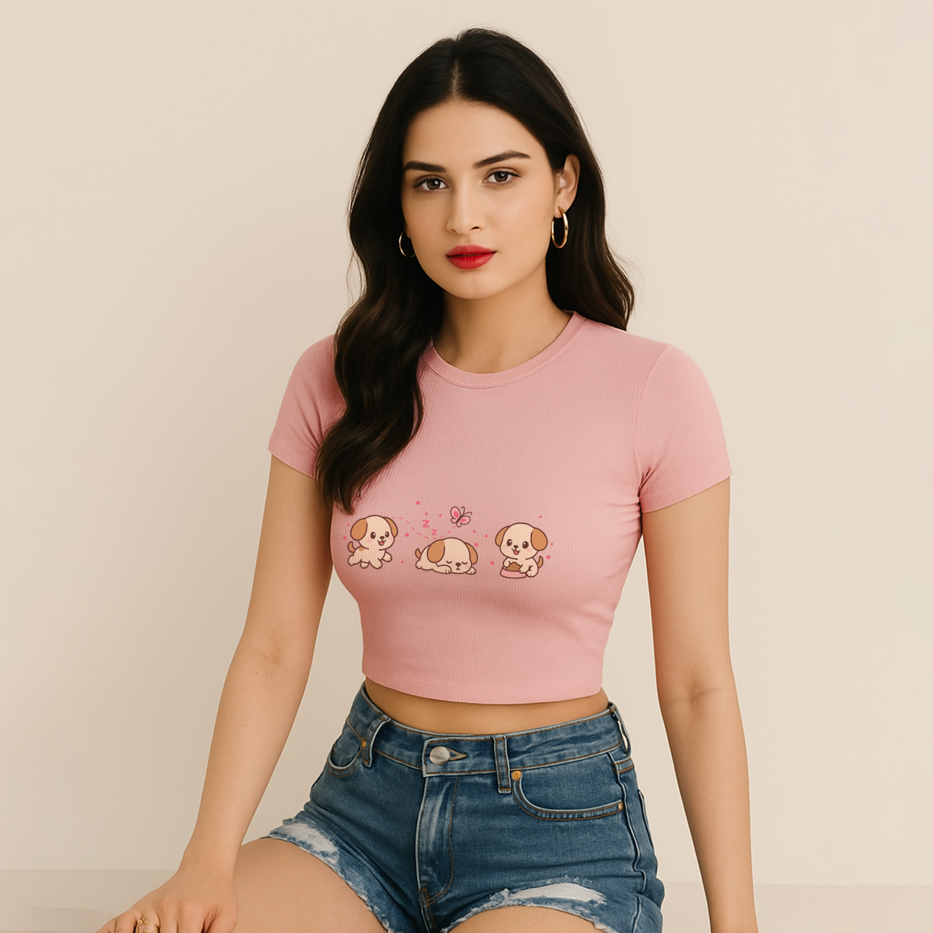 Light Baby Pink Cute Dog Baby Tee with cute dogs design on the front worn by a female model sitting on the floor